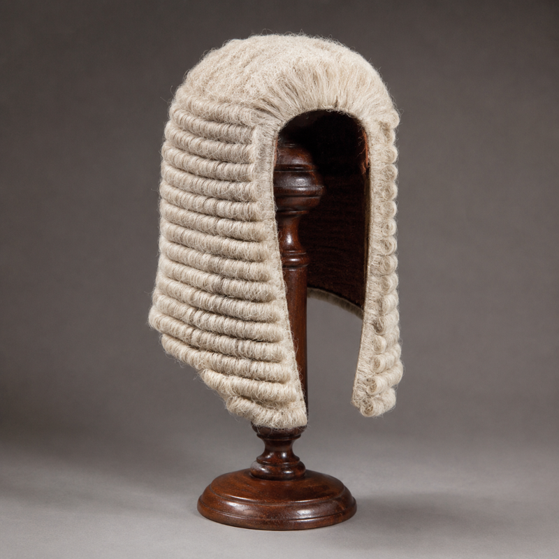 An ornate wig on a wooden stand